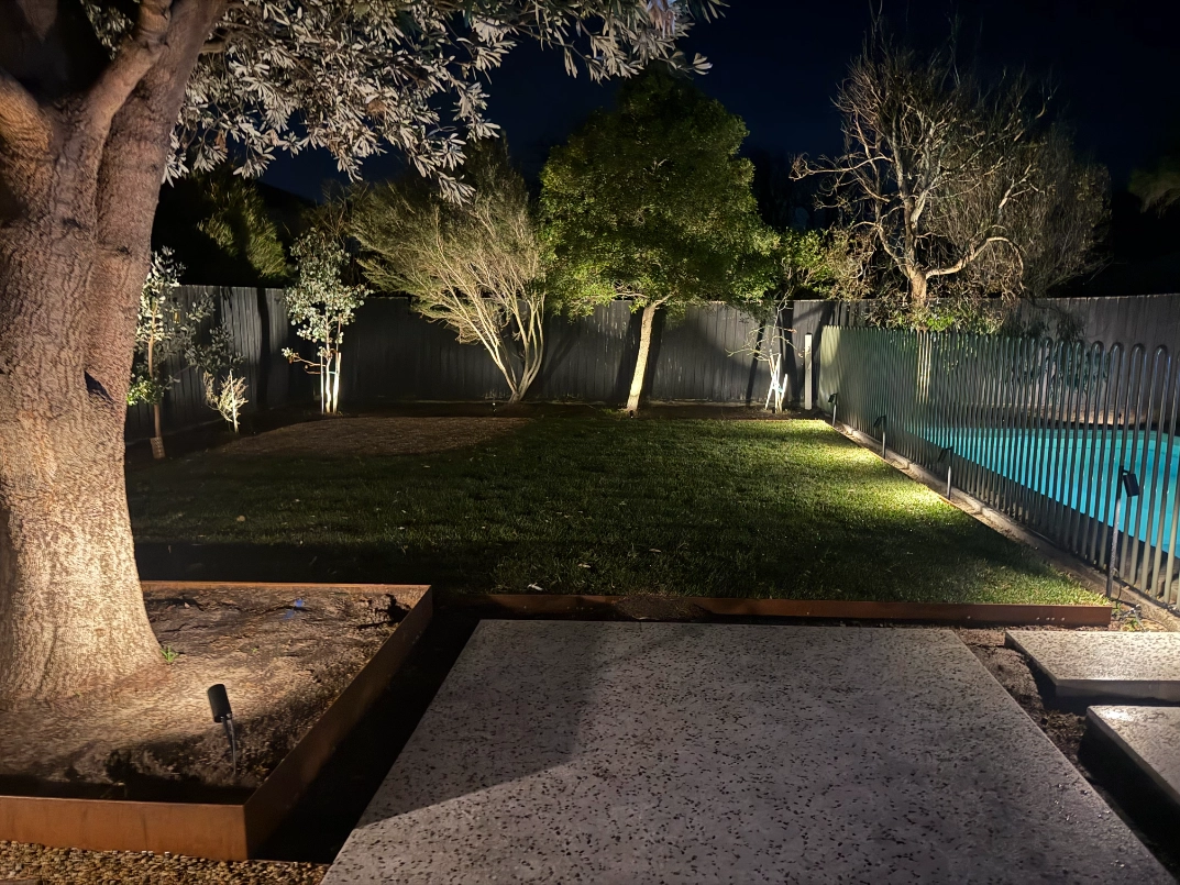 Securelec landscape lighting illuminating a garden and pool area
